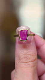 A vintage-inspired, pink ruby solitaire engagement ring in yellow gold, showing the ring details in video held between fingers.