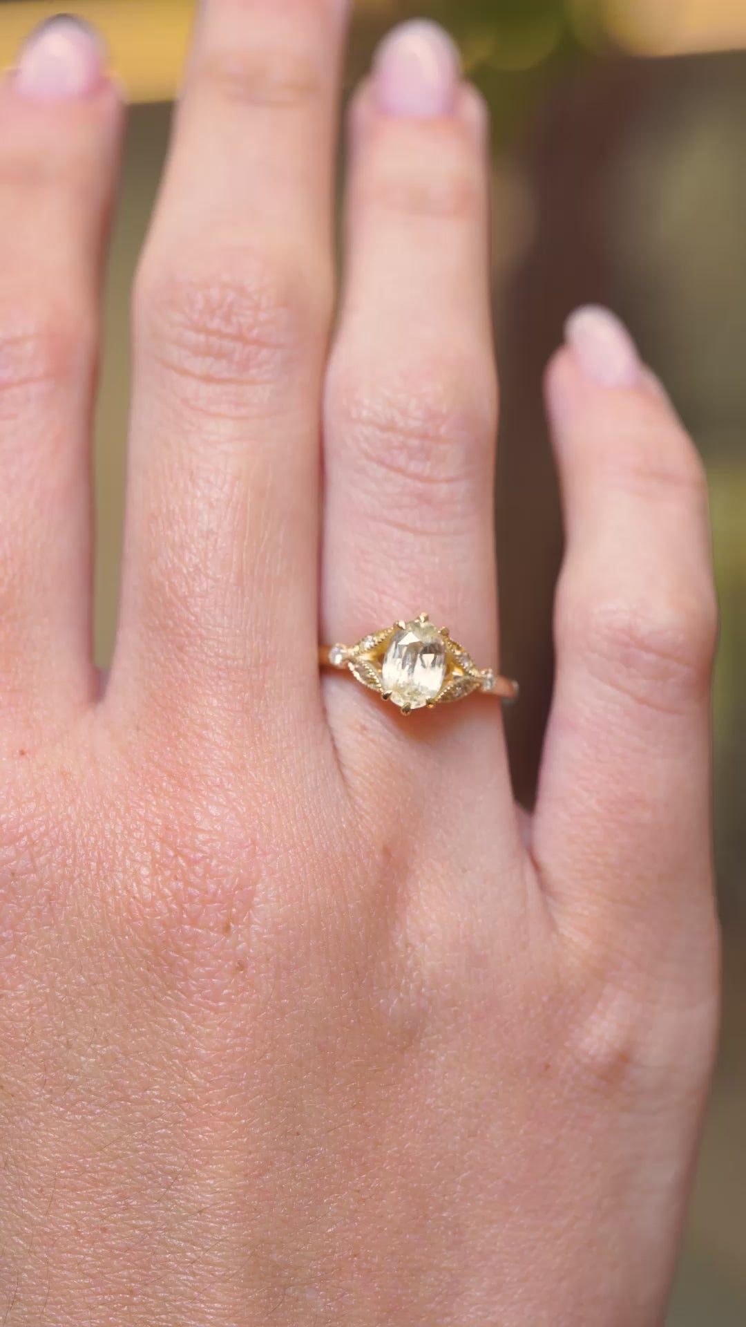 A video of an oval-cut yellow sapphire and diamond engagement ring displayed on the hand in a yellow gold setting.