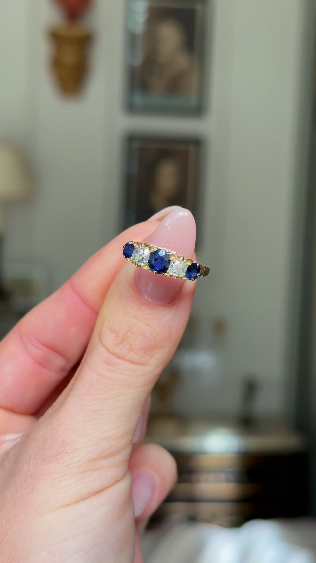 edwardian sapphire and diamond five stone ring held in fingers and rotated to give perspective. 