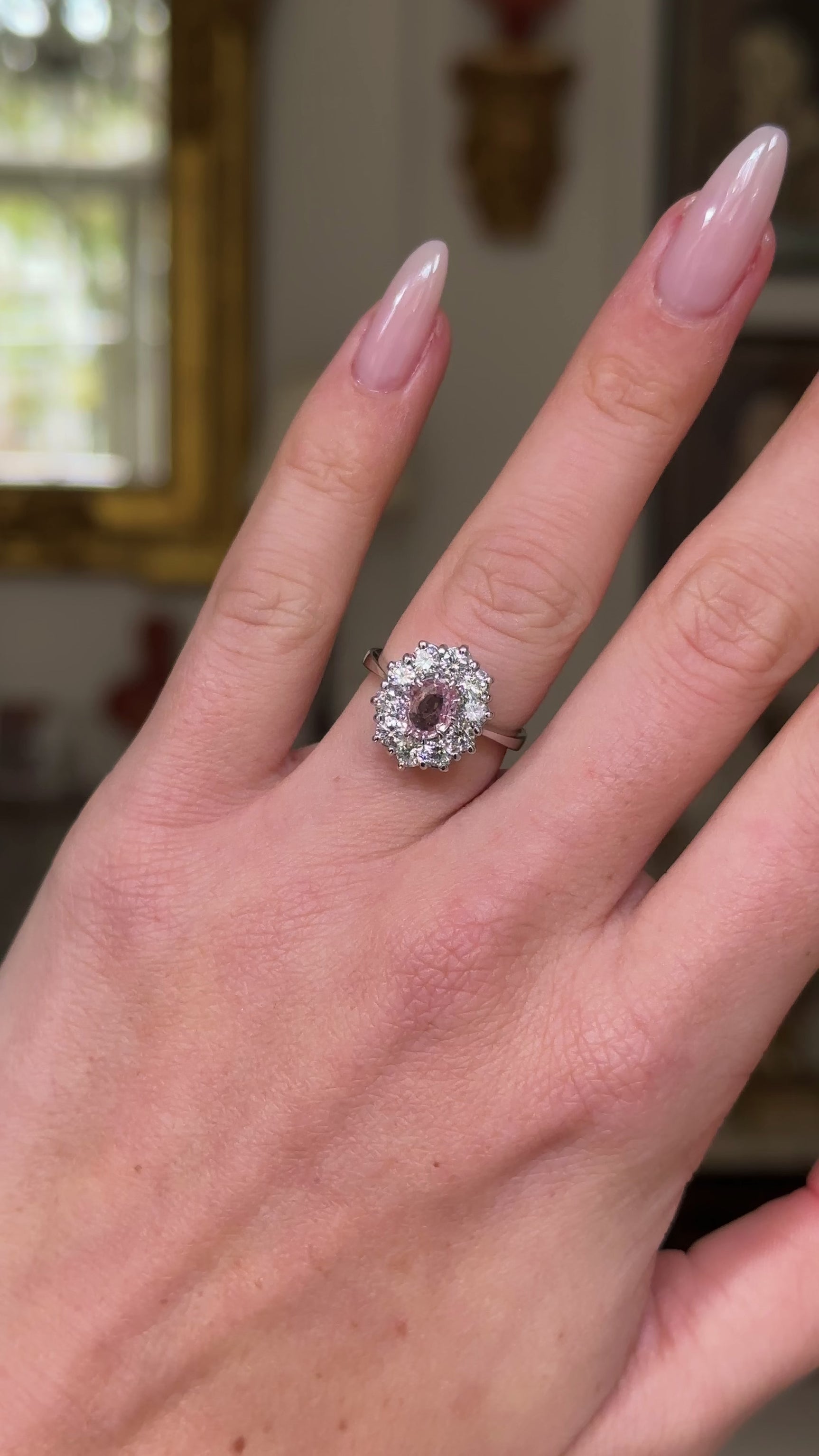 Peach pink sapphire diamond cluster ring worn on hand and moved around to give perspective.