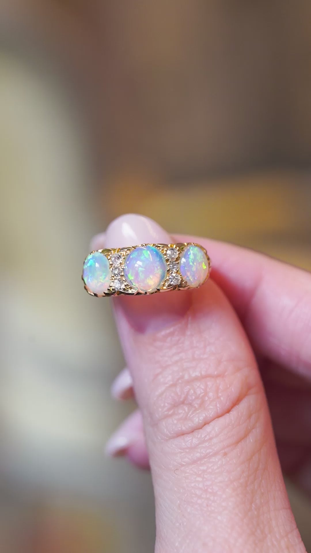 Close detail video of antique Edwardian opal and diamond three-stone ring with glowing opals.