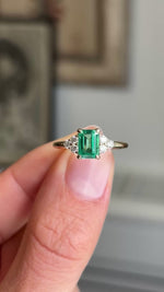 Video of an antique-inspired, Emerald and diamond cluster trefoil engagement ring in yellow gold against a blurred background