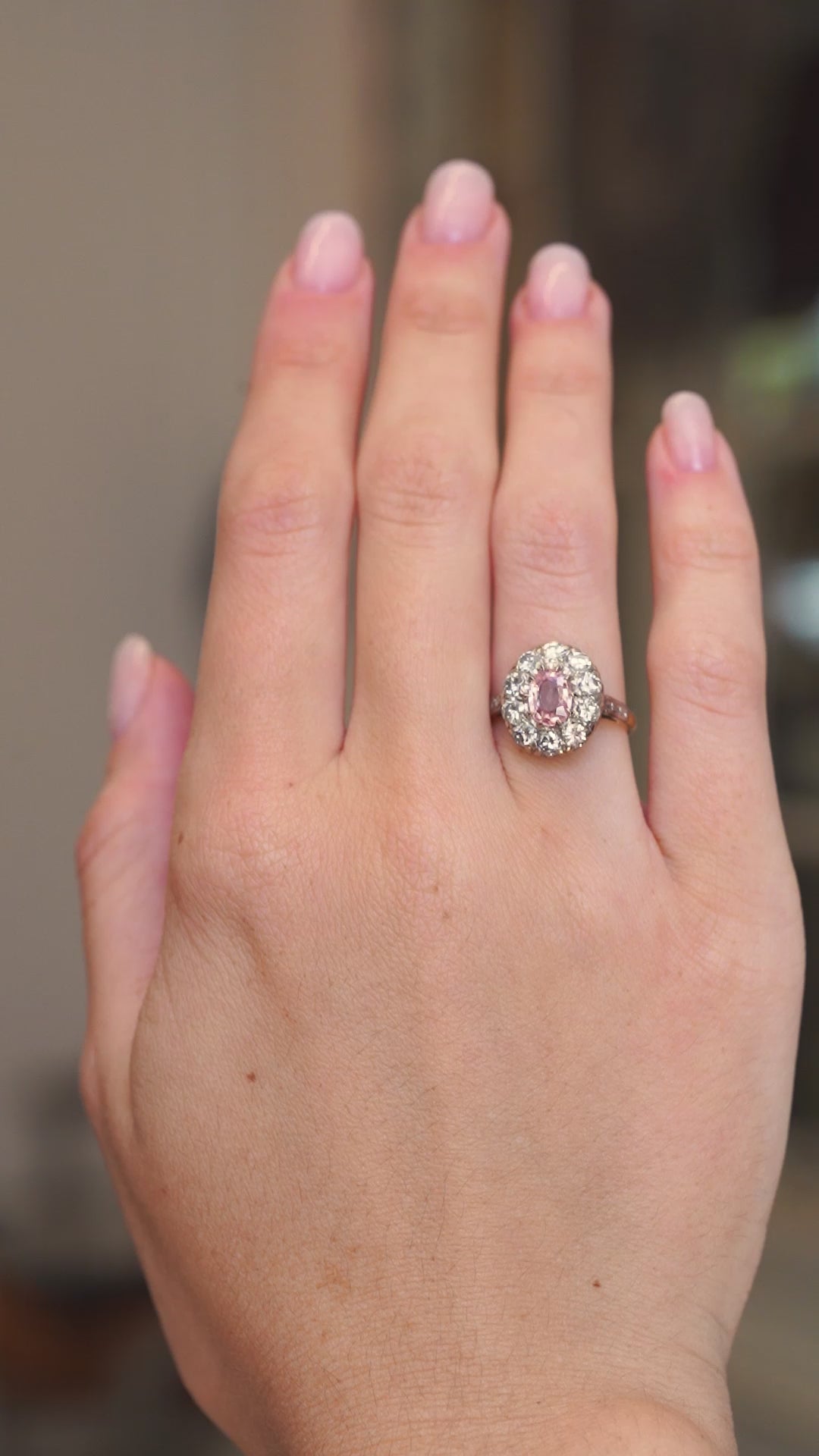 Vintage orange-pink sapphire and diamond cluster ring worn on the hand shown in video in a subtle motion.