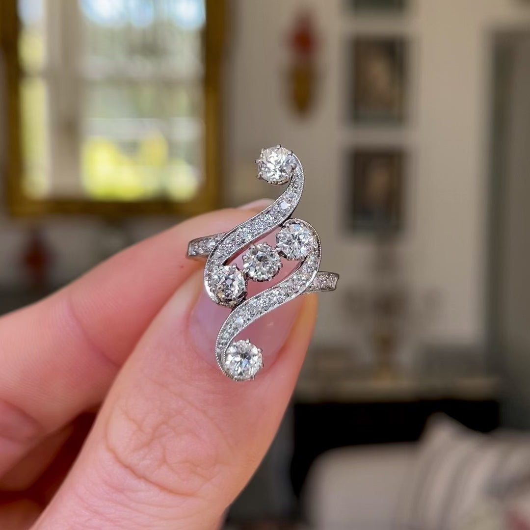 Art Nouveau diamond engagement ring, held in fingers and rotated to give perspective.