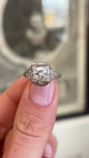 Antique Art Deco diamond cluster ring showcasing a geometric diamond cluster design with ornate openwork detailing, held by hand for detailed viewing.