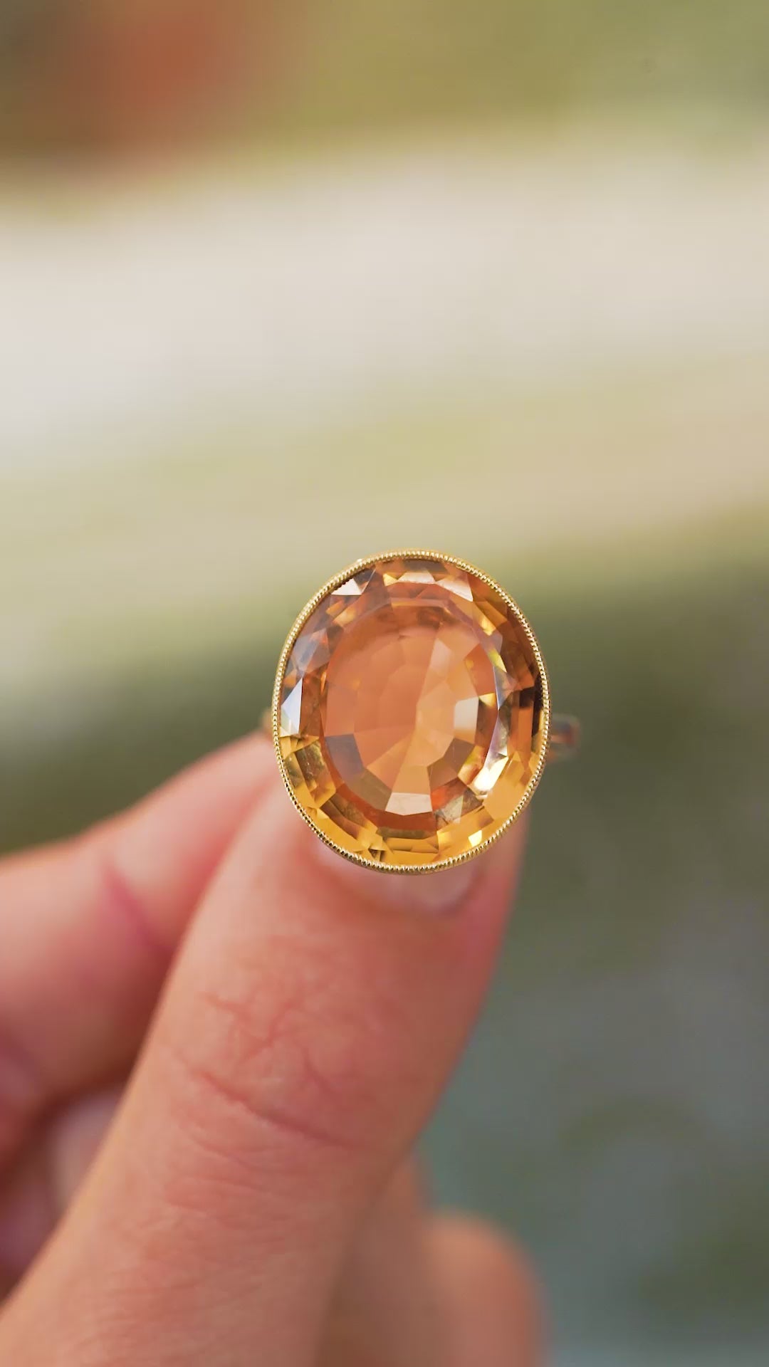 Large orange topaz ring showing faceted gemstone and raised gold setting detail.