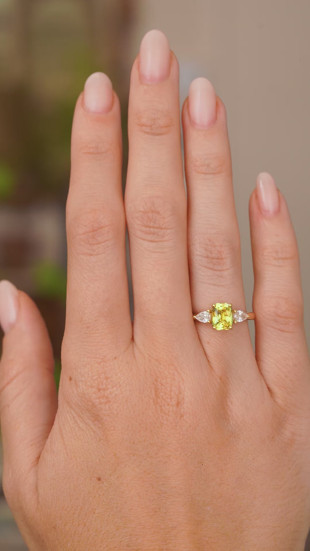 A video of an Antique-inspired, emerald-cut yellow sapphire and diamond three-stone ring shown for scale