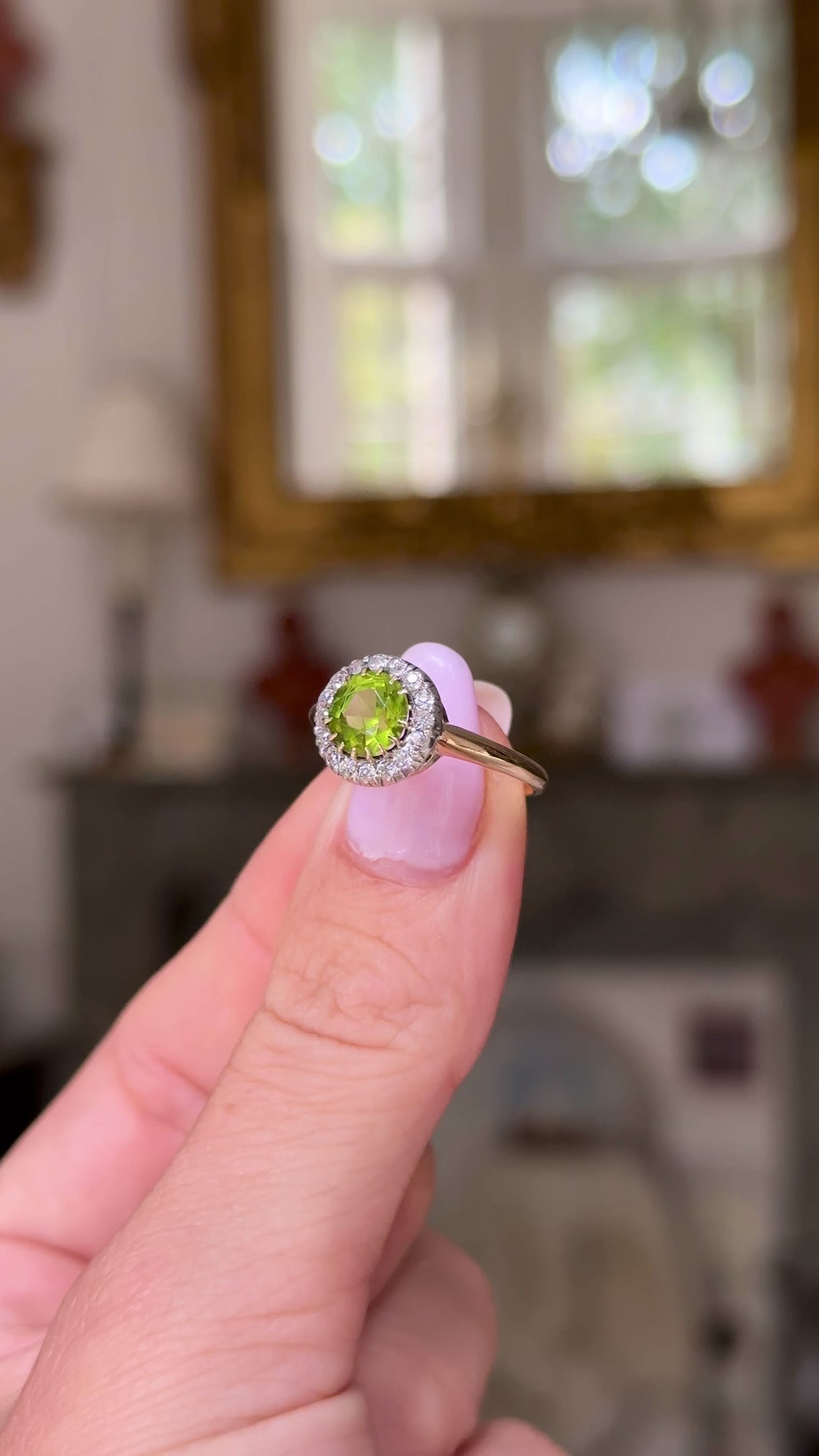 Edwardian peridot and diamond cluster ring, held in fingers and rotated to give perspective.