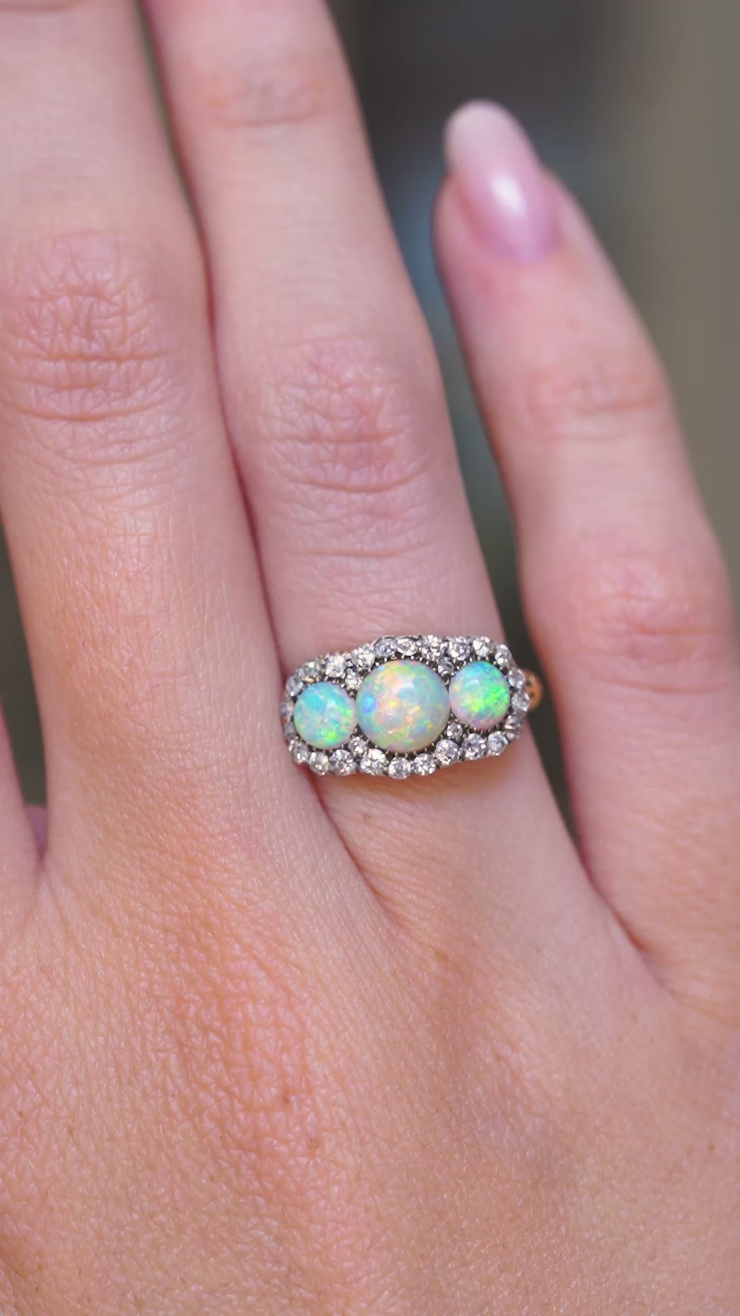 A video of an antique, Victorian three-stone opal & diamond cluster ring showing how it's worn on a hand.
