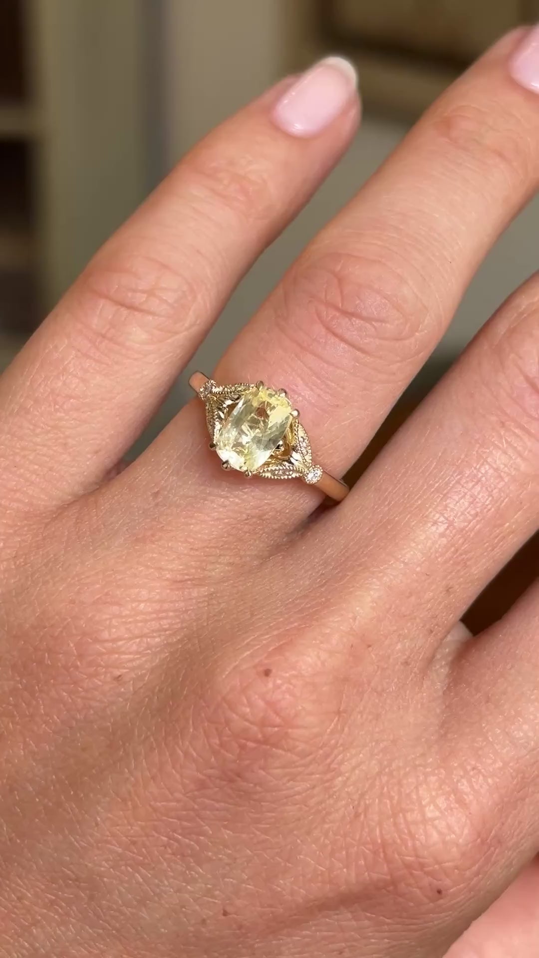 Video of a Vintage-inspired yellow cushion-cut sapphire & diamond engagement ring worn on an engagement finger and slowly rotated to display the angles of the ring. 