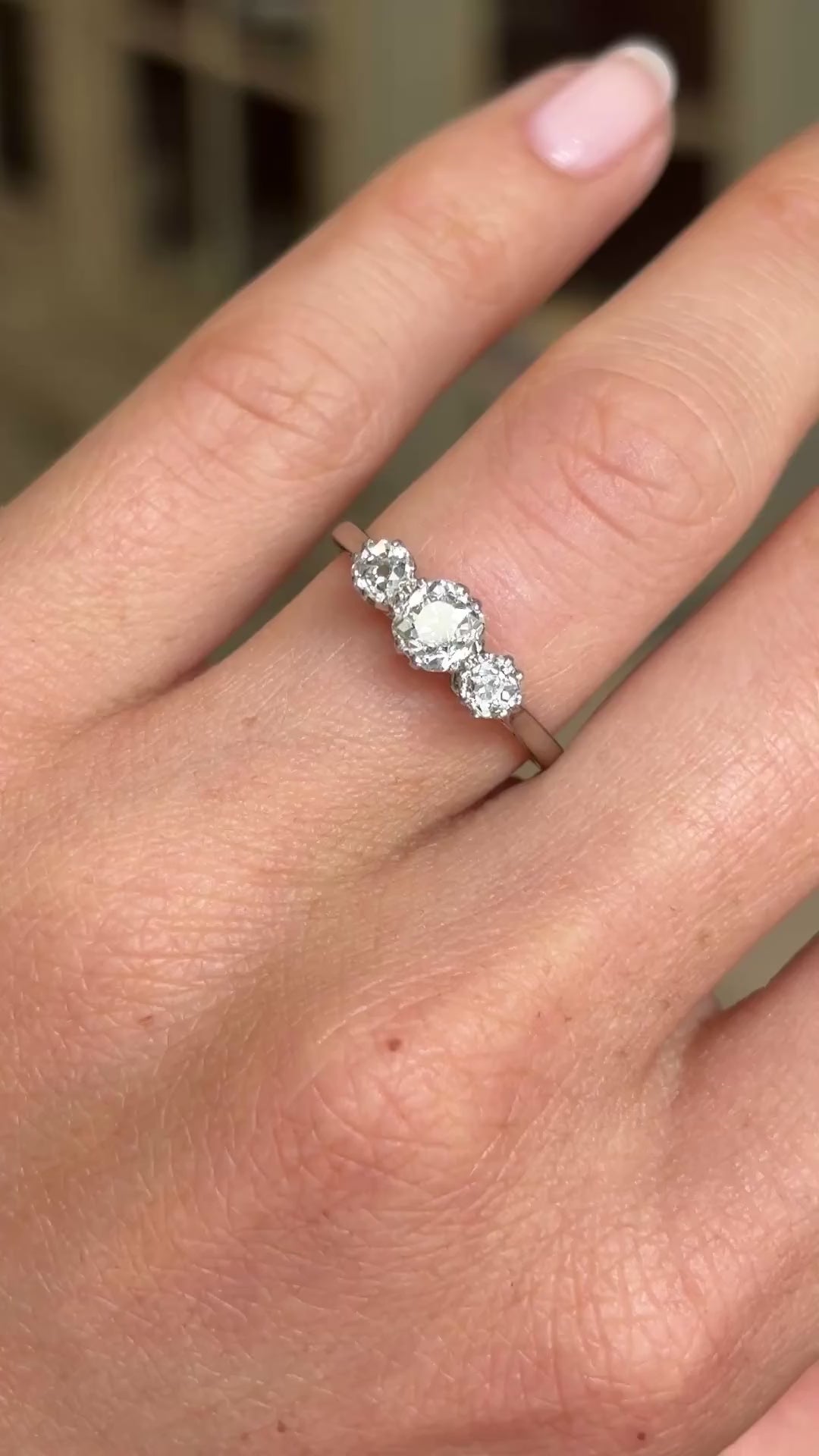 A close up video of a vintage three-stone old-cut diamond engagement ring in white gold worn on a wedding finger. 