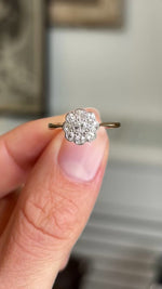 Close up video of two fingers holding an Antique Antique, Edwardian diamond daisy cluster ring, rotated slowly to display the nine old-cut diamonds and yellow gold band. 