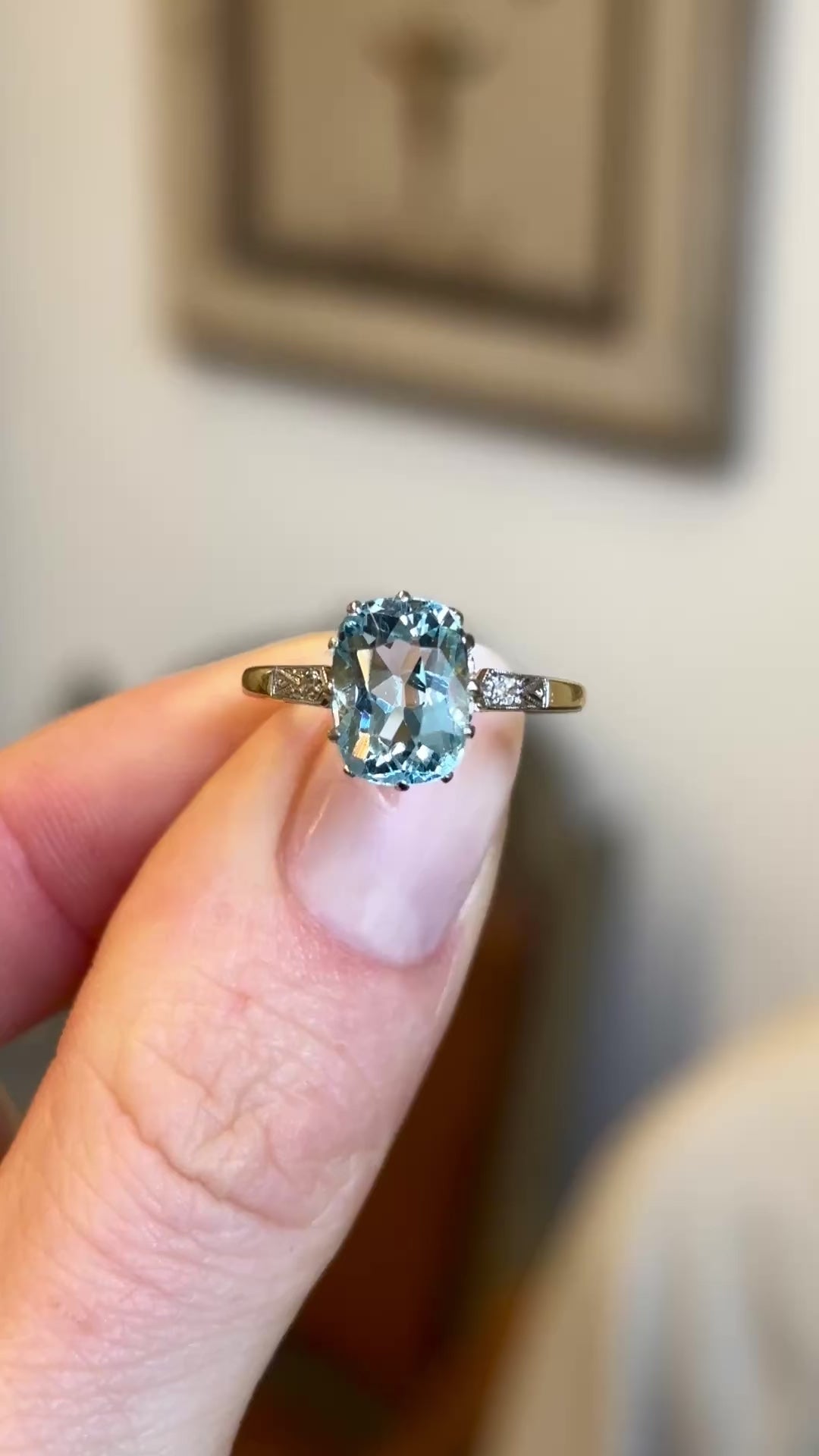 Video of an antique Edwardian cushion-cut aquamarine and diamond engagement ring next to a window, showing the aquamarine’s colour and diamond brilliance in natural light.