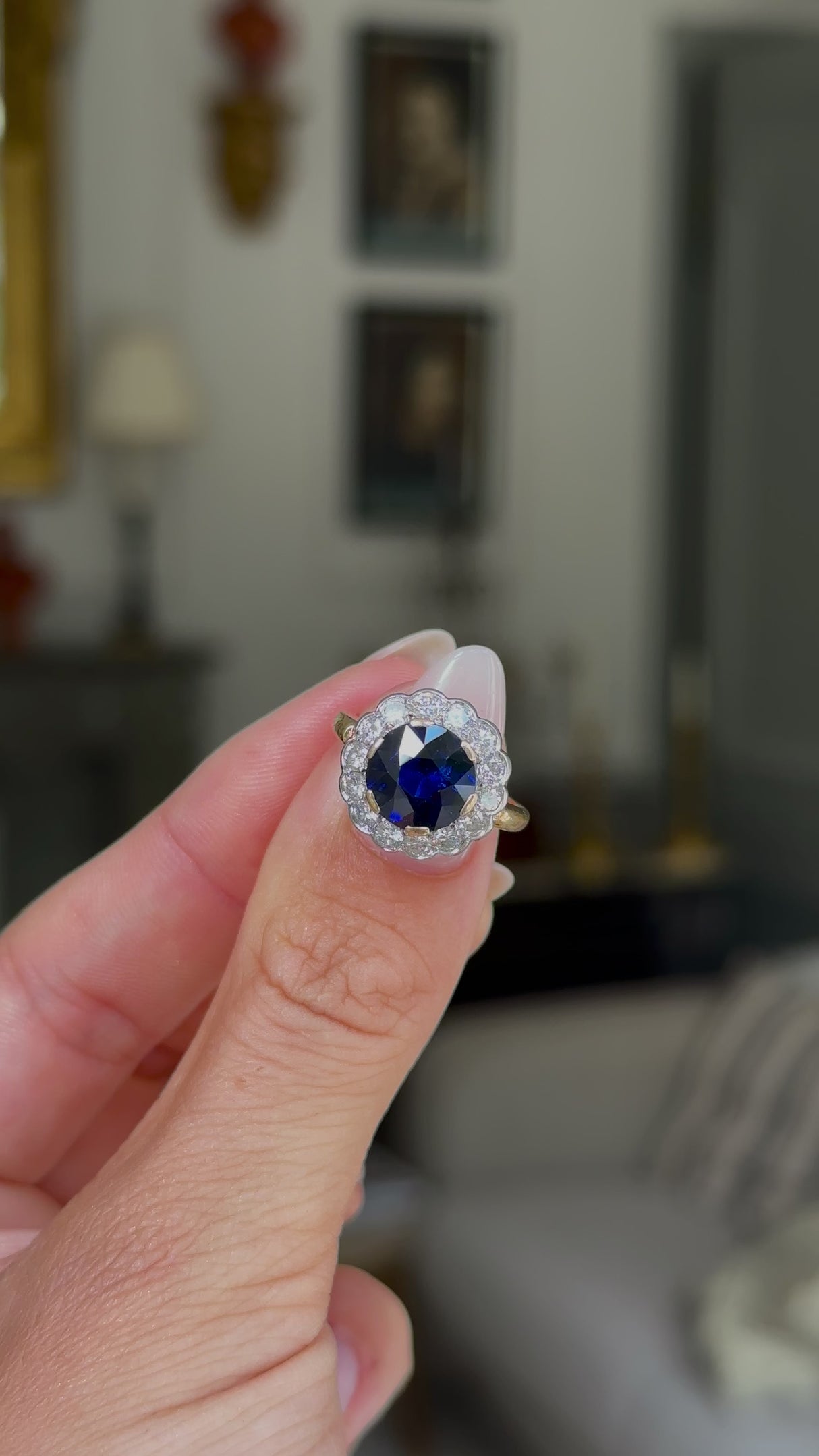 belle epoque sapphire and diamond cluster ring, held in fingers and rotated to give perspective,front view.