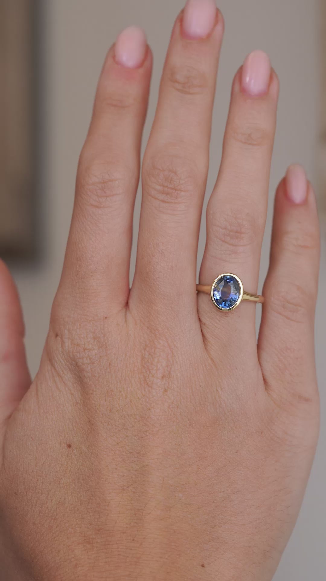 Video showcasing the oval sapphire ring on the hand from a wider perspective, with the yellow gold setting framing the gemstone.