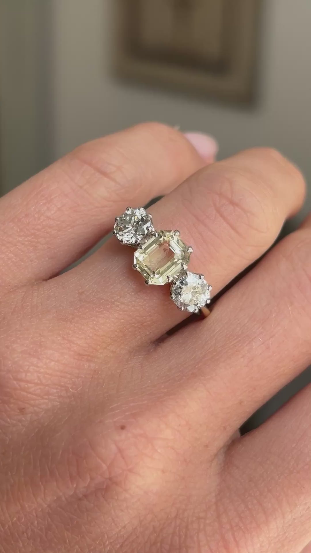 Vintage 1970s yellow sapphire and old-cut diamond three-stone engagement ring featuring a yellow sapphire centre stone flanked by old-cut diamonds, displayed on a hand.