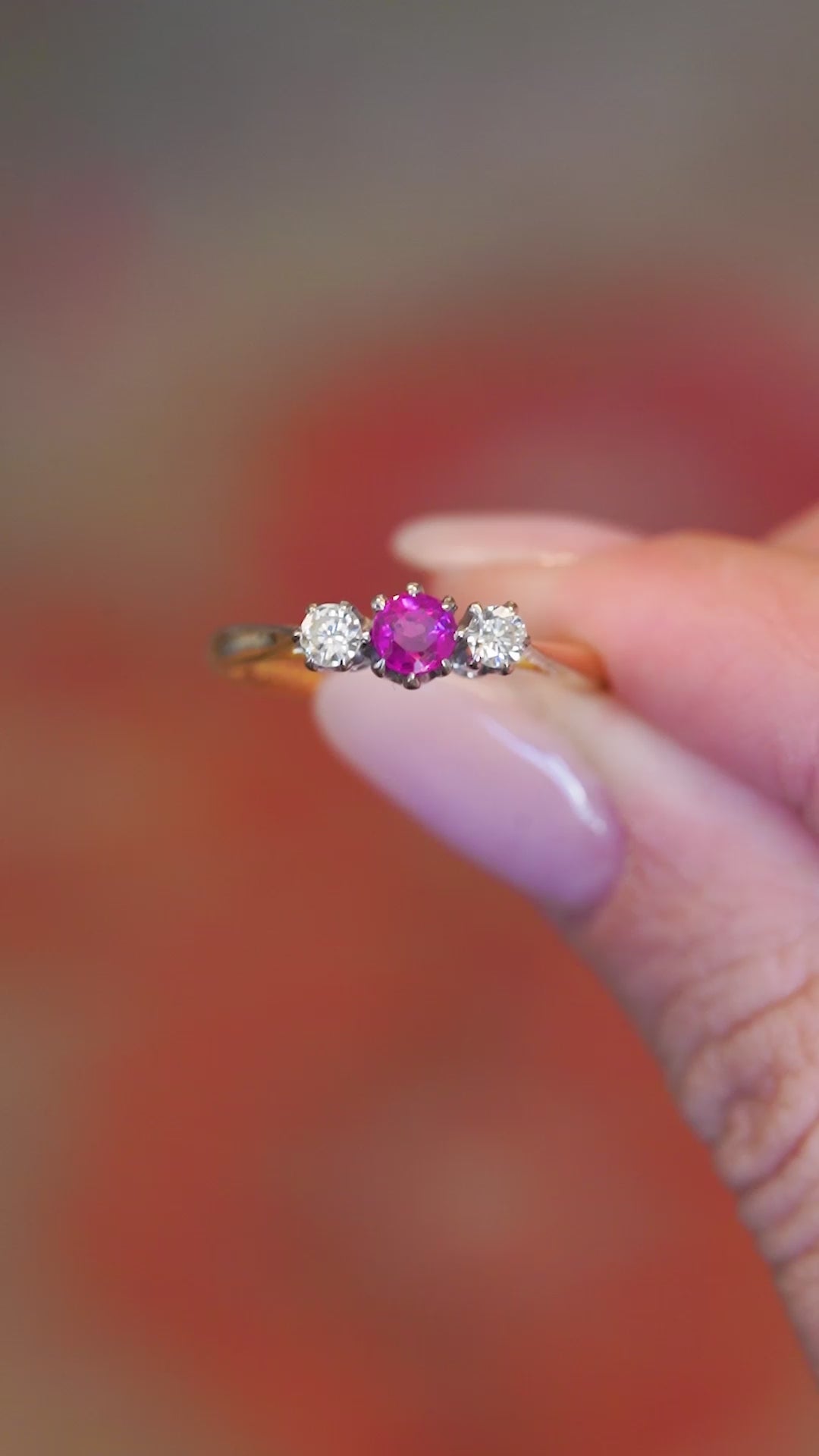 Close detail video of vintage ruby and diamond three-stone ring with gold setting.