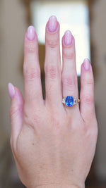 Vintage 1990s sapphire and diamond three-stone ring worn on hand with vivid blue sapphire catching the light.