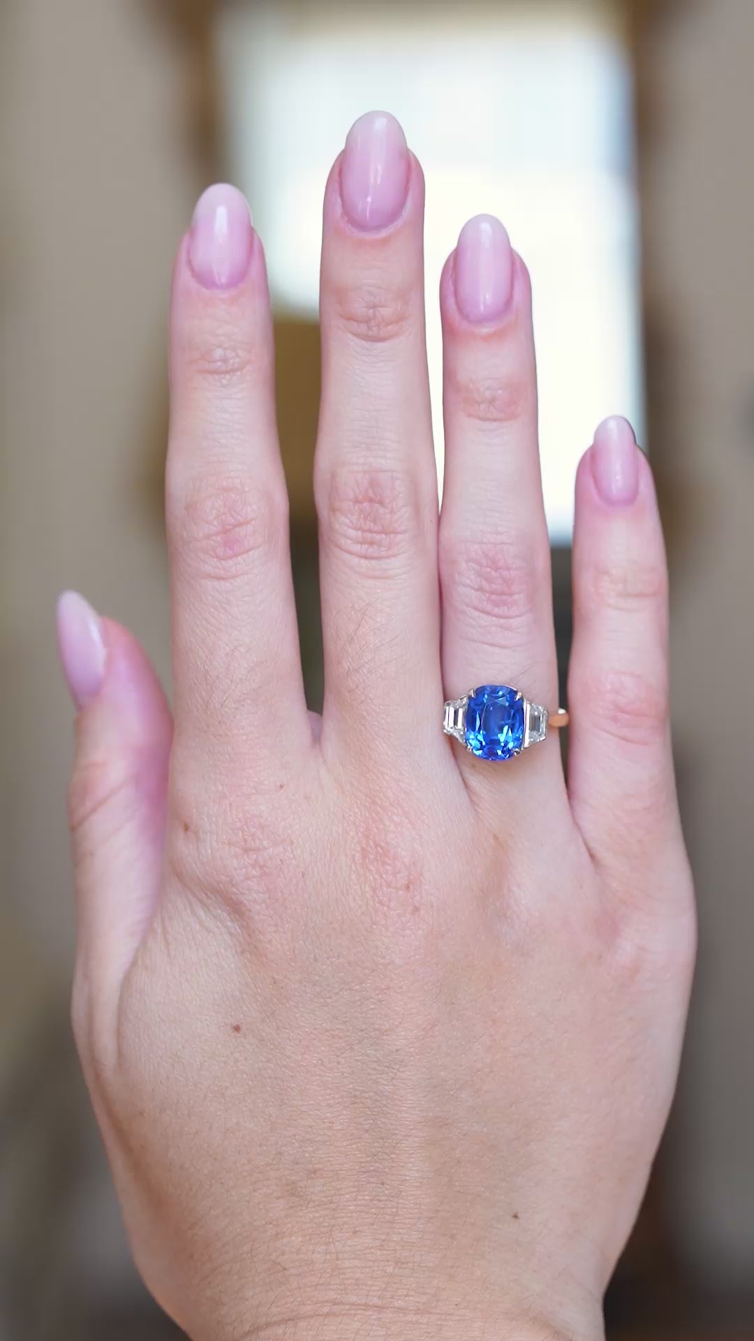 Vintage 1990s sapphire and diamond three-stone ring worn on hand with vivid blue sapphire catching the light.
