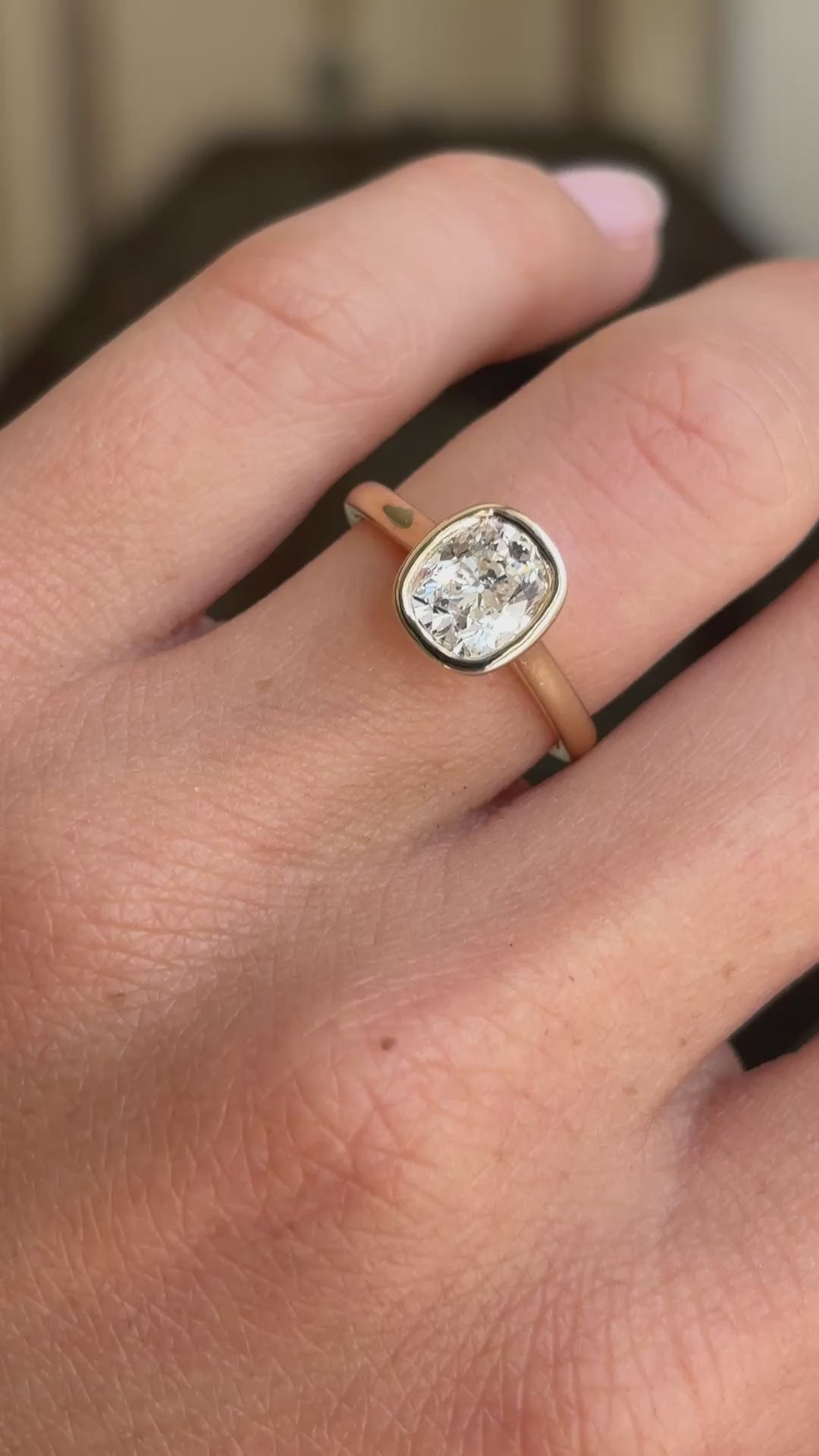 Antique-inspired cushion old-cut diamond solitaire engagement ring displayed on a hand, featuring a cushion-shaped old-cut diamond in a classic solitaire setting.