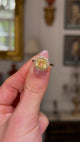 Vintage, Cushion-cut Yellow Sapphire Diamond Cluster Engagement Ring, held fingers and rotated to give perspective, front view. 