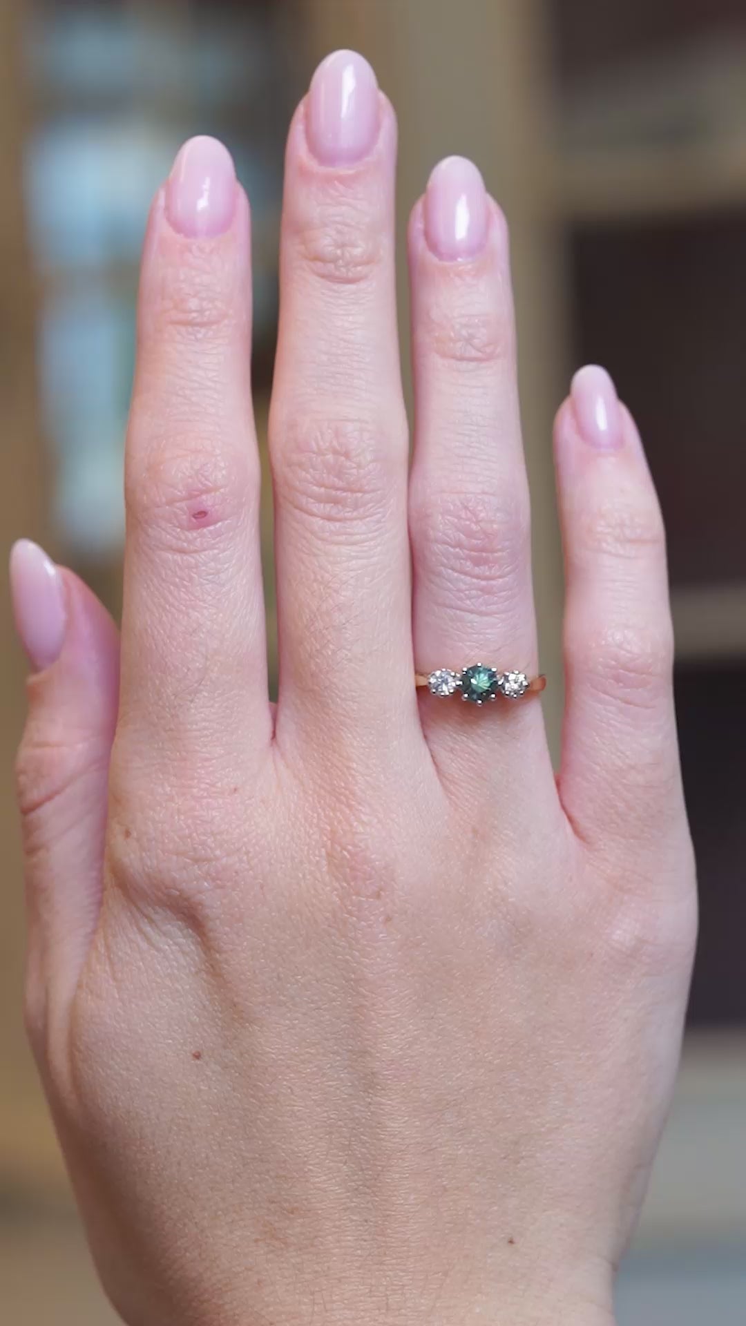 Vintage 1950s green sapphire and diamond three-stone engagement ring worn on hand in motion.