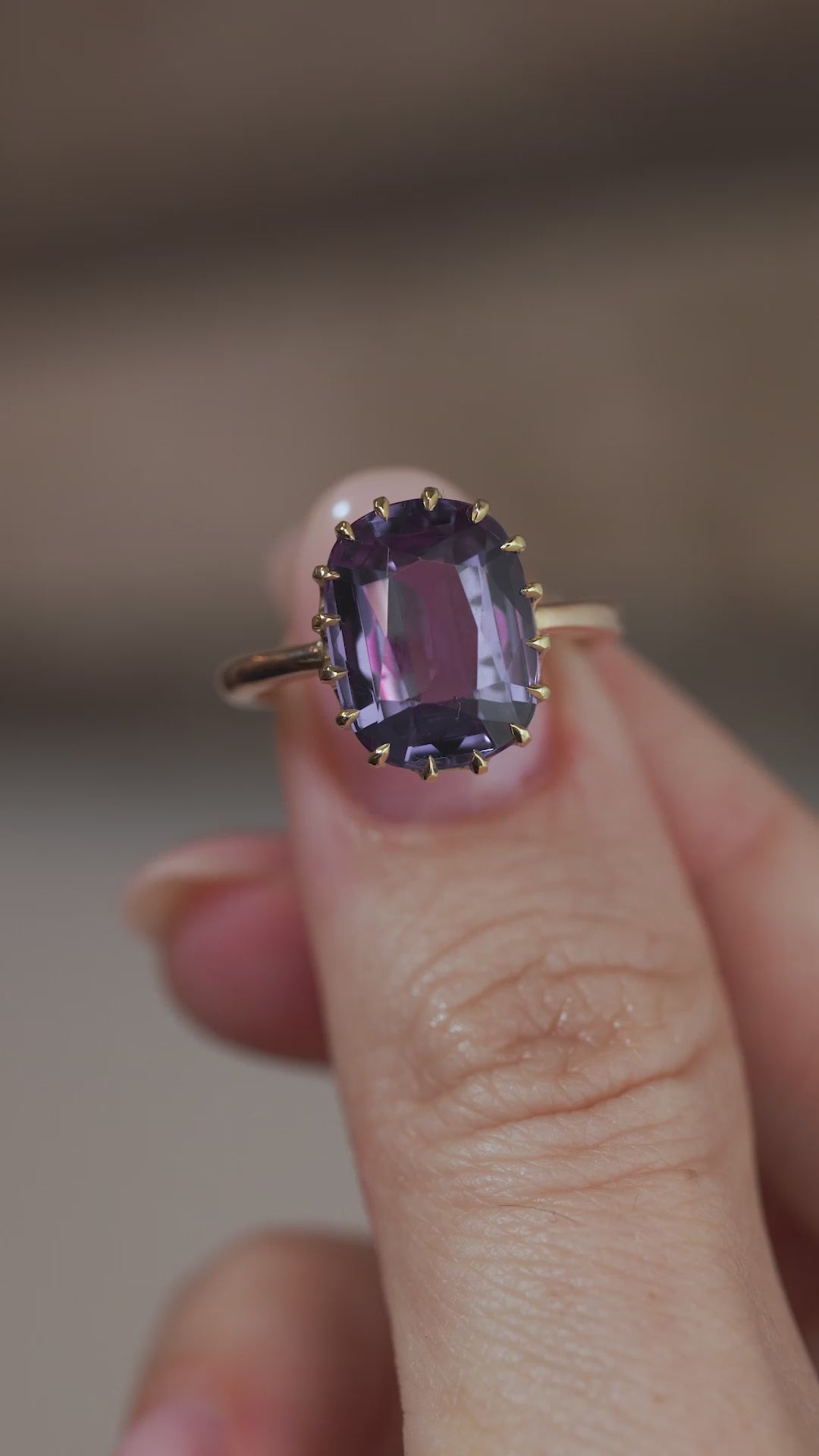 A close-up video of the Edwardian synthetic sapphire ring held between fingers, showcasing the gemstone's facets and changing colour reflections.