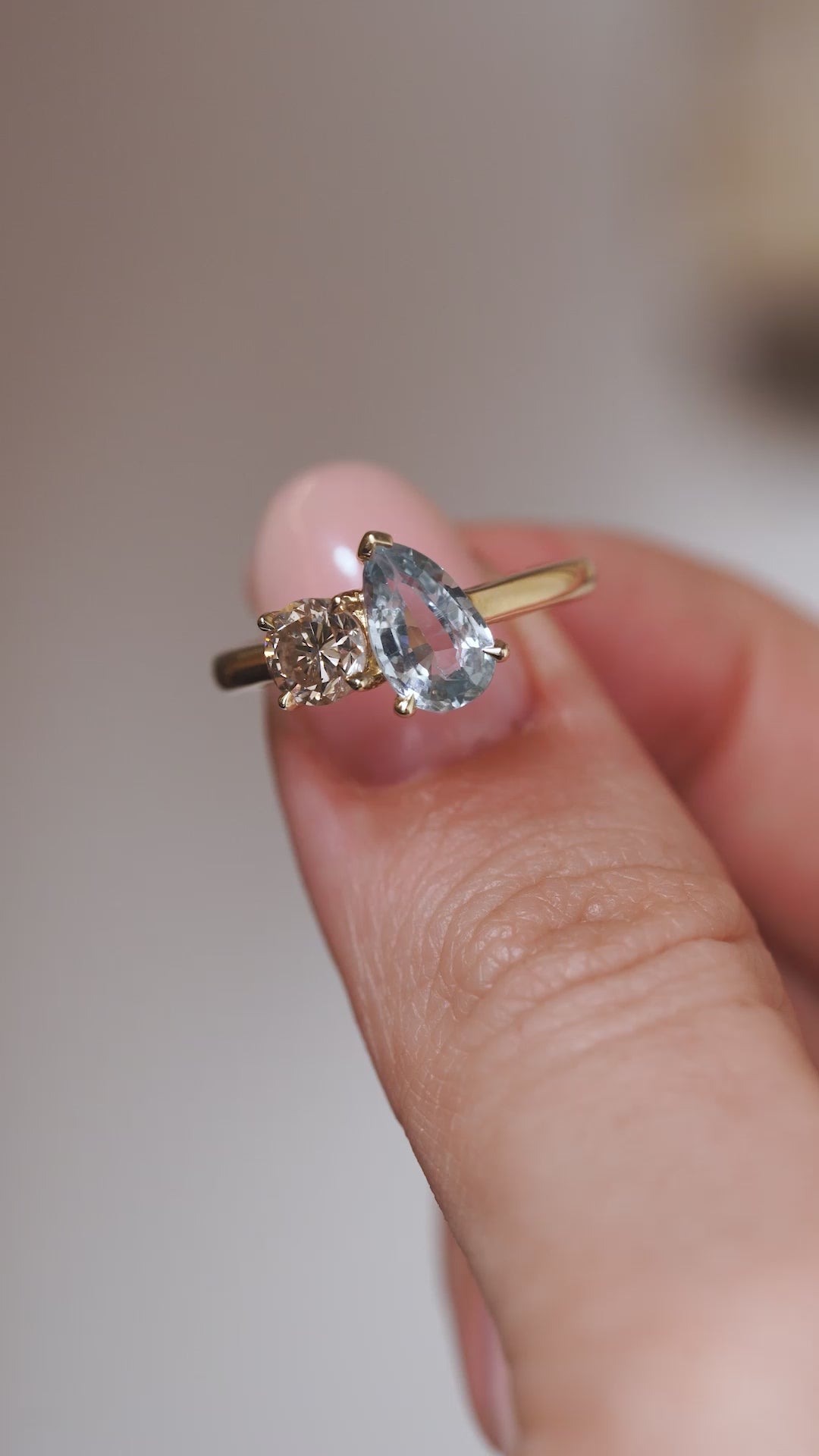 A close-up video of the sapphire and diamond ring held between fingers, showcasing the contrasting gemstone shapes and sparkle.