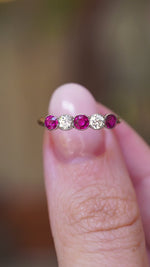 A video of an antique Edwardian ruby and old-cut diamond five-stone ring held between fingers.
