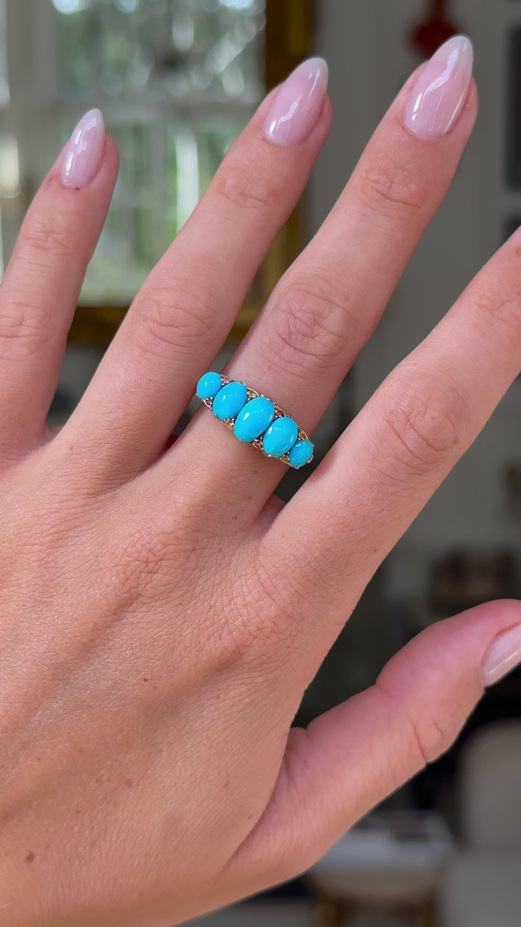 turquoise five stone half hoop ring, worn on hand and moved away from lens to give perspective, front view. 