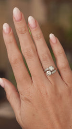 A video of a hand out stretched wearing an antique 1905 diamond two stone engagement ring in yellow gold shown for scale.