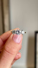 Close up video of a three-stone diamond engagement ring from the Edwardian era.  Held between two fingers and rotated slowly to showcase the profile of the ring and the yellow gold band