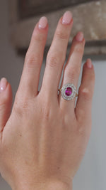 A close-up video of an antique Edwardian Burmese ruby and diamond cluster engagement ring modelled on a hand, showcasing the vivid ruby and sparkling double diamond surround.