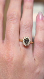 A video of a green sapphire and diamond cluster engagement ring displayed on the hand in yellow gold.