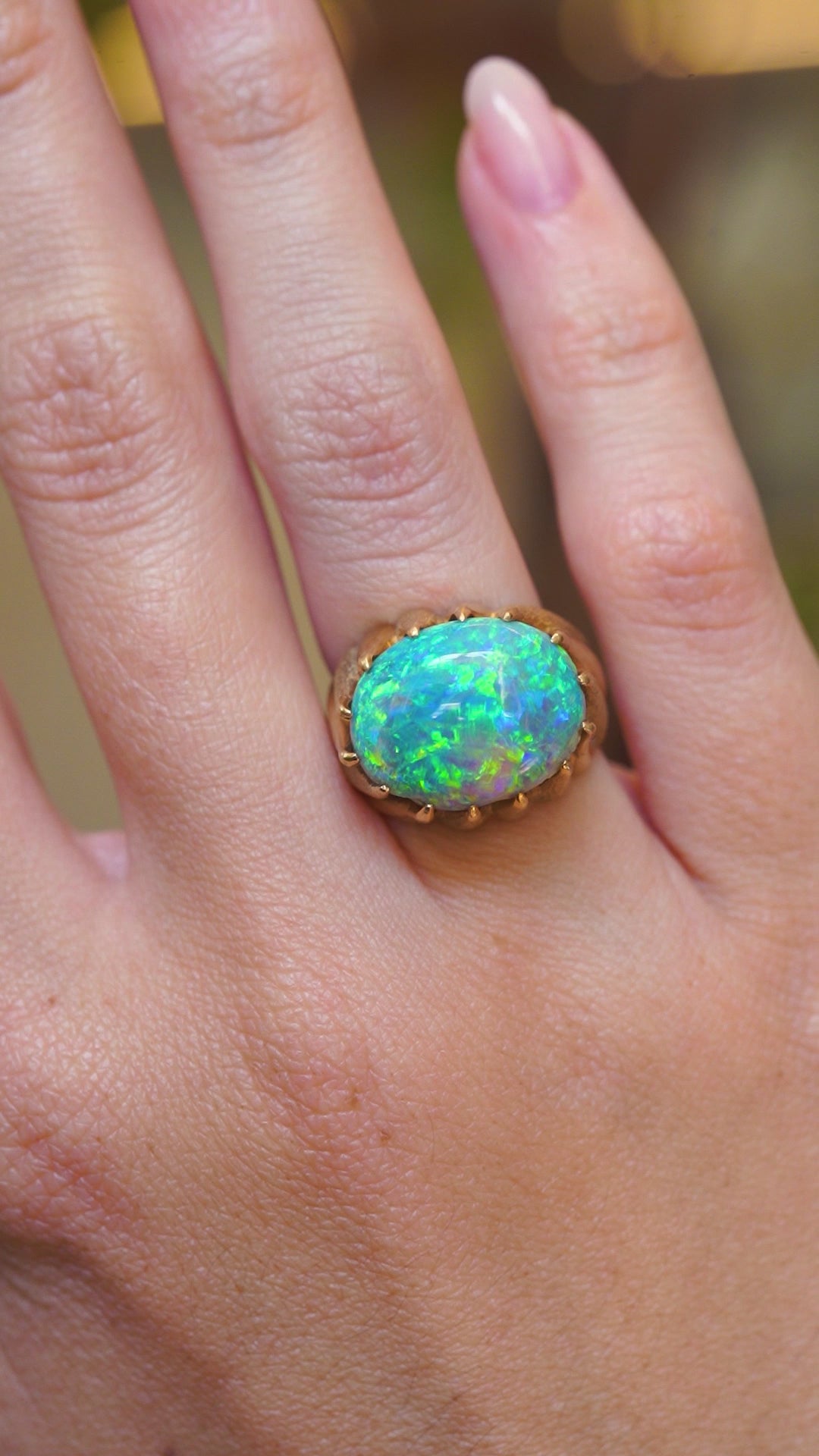 A video of a vintage oval cabochon Australian opal ring in yellow gold shown on a hand.
