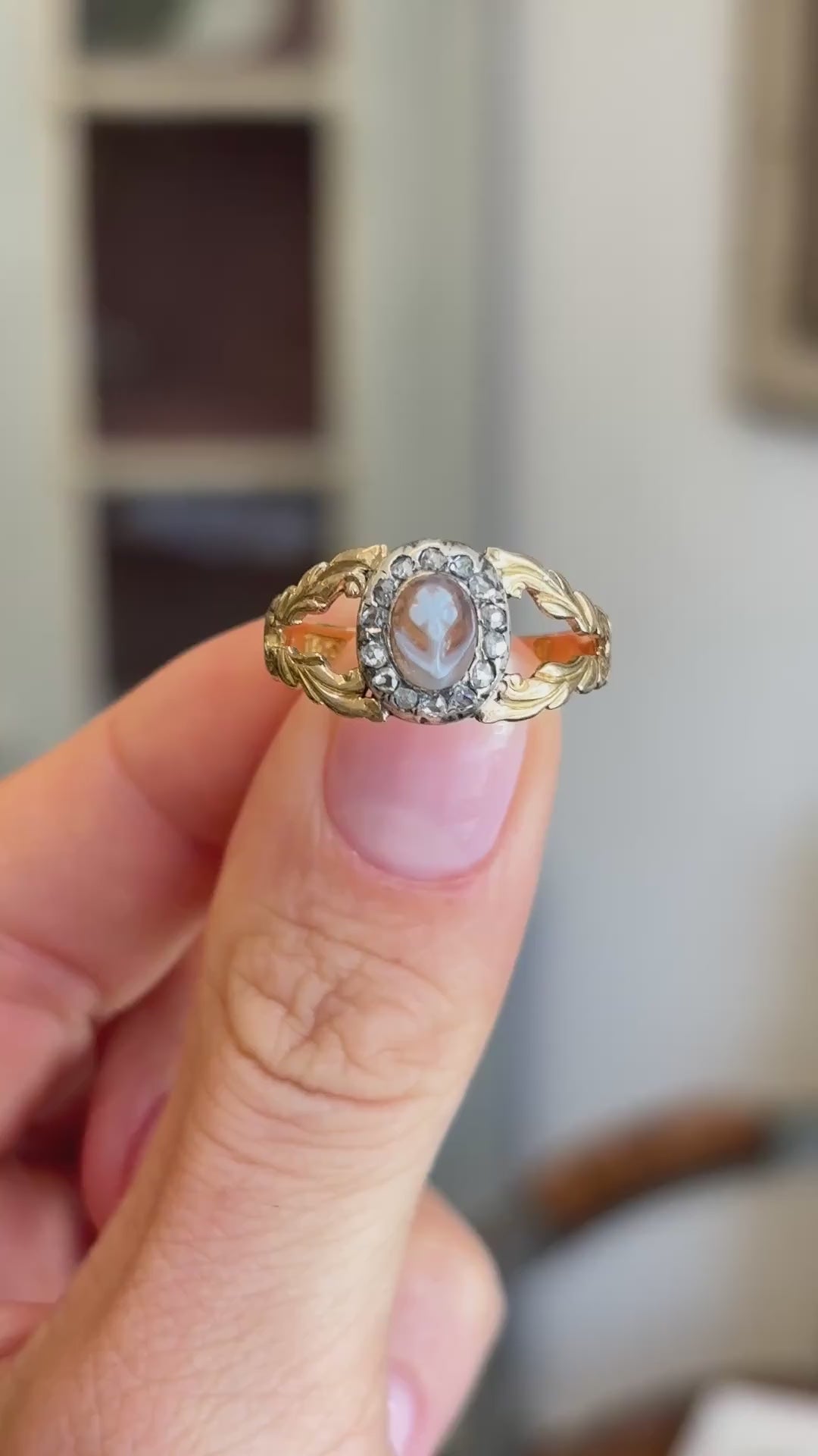 Antique Georgian forget-me-not cameo cluster ring showcasing a carved forget-me-not cameo and decorative cluster design, held by hand to highlight the craftsmanship.