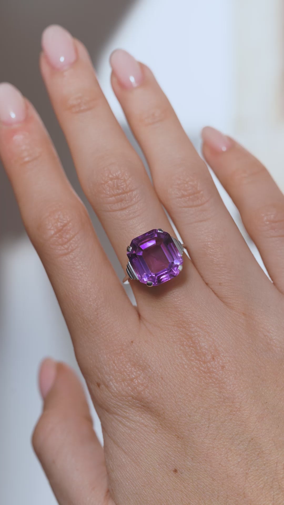 A video of the Art Deco amethyst ring worn on a finger, capturing the gemstone's vibrant purple tones and distinctive step-cut facets.