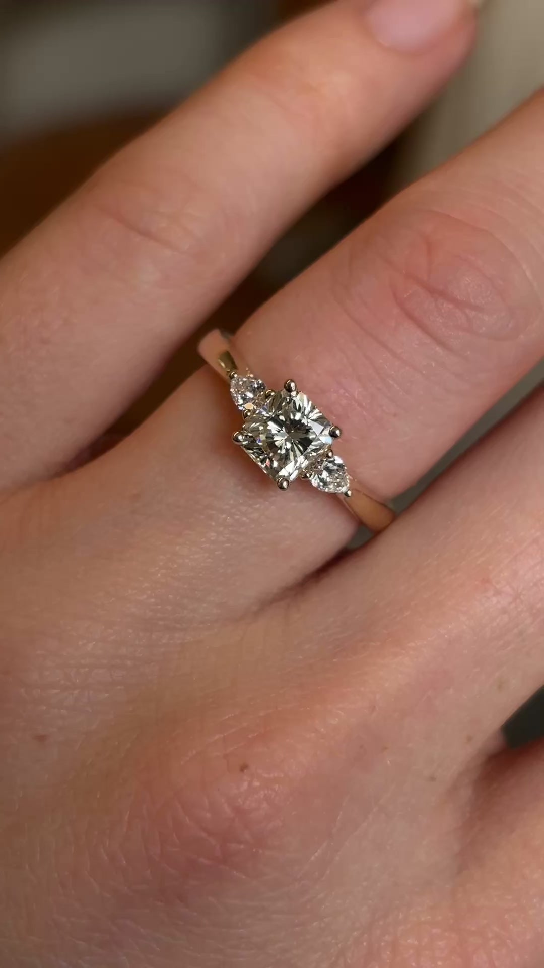 Diamond three-stone engagement ring worn on hand at a distance to show scale