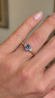 Close up video of an antique-inspired three-stone yellow gold engagement ring, set with a central cornflower blue sapphire and two diamonds worn on a wedding finger.   