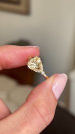 Video of a Vintage-inspired yellow gold engagement ring, set with a pale yellow cushion-cut sapphire flanked by diamonds.  Held between two fingers and rotated slowly to showcase the stones.