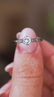 A close up video of an Antique, 1930s Art-Deco diamond flanked solitaire engagement ring in platinum.  Held between two fingers and rotated slowly to display the profile of the ring.