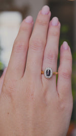 A video of a yellow gold Antique, Edwardian sapphire and diamond coronet cluster engagement ring worn on the hand  as the fingers move, shown against a blurred background.