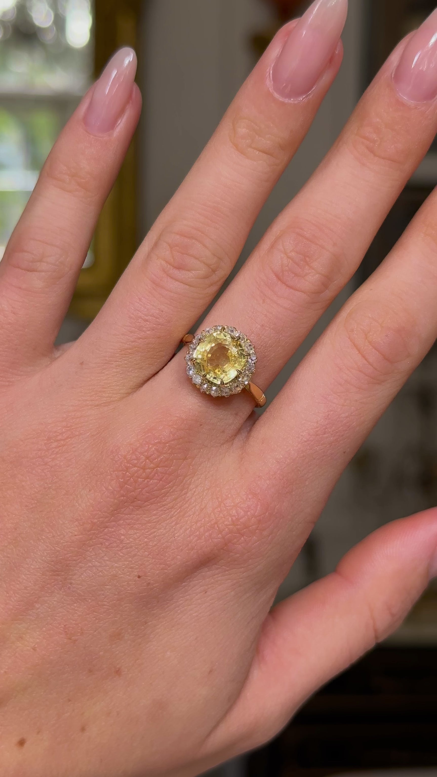 Vintage, Cushion-cut Yellow Sapphire Diamond Cluster Engagement Ring, worn on hand and moved away from lens to give perspective, front view. 