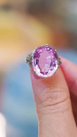 Art Deco pink topaz and diamond ring showing large oval topaz and diamond set shoulders between fingers.