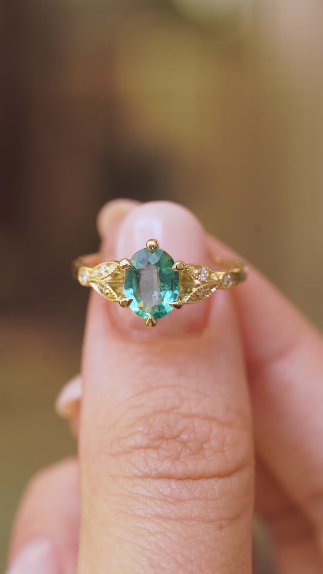 a video of Vintage-inspired, Emerald and diamond engagement ring held between fingers and turned to show off different angles