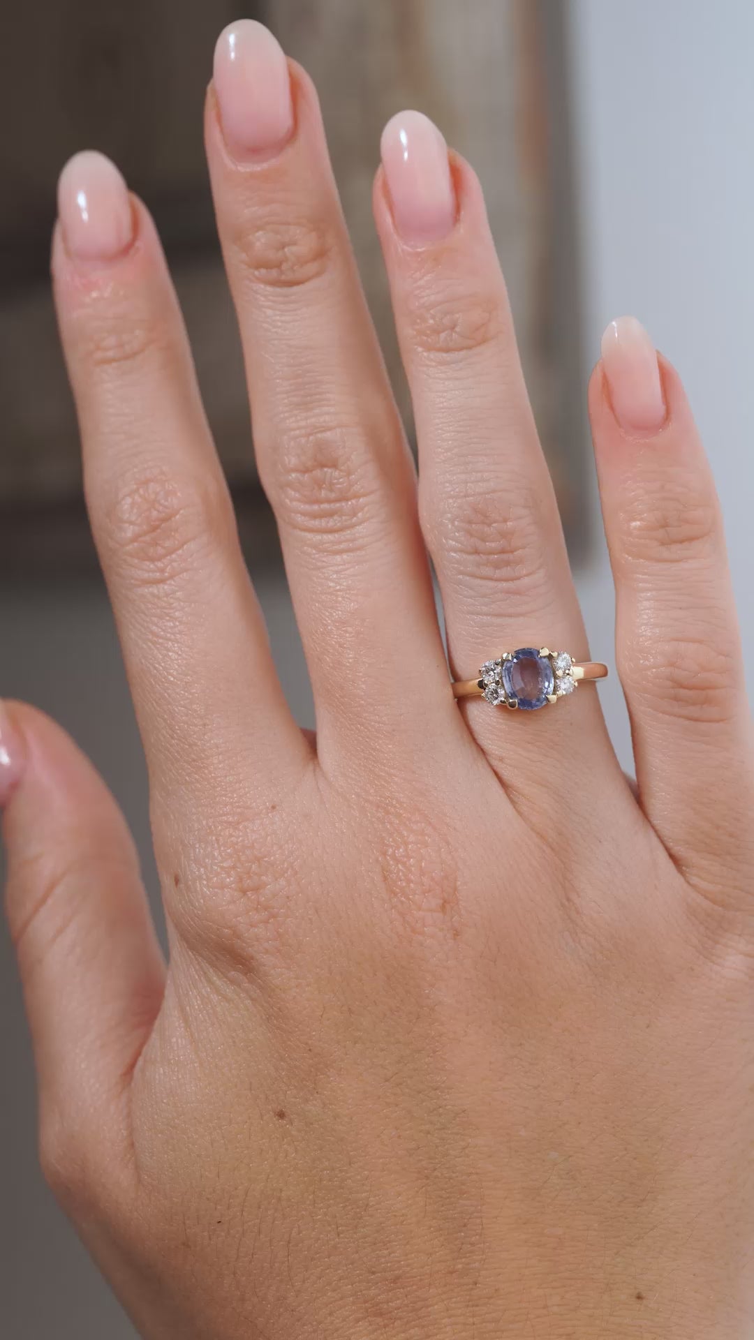 A video of the vintage-inspired blue sapphire and diamond cluster engagement ring worn on a hand, showcasing the oval sapphire, sparkling side diamonds and elegant yellow gold band.