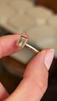 Video of a Vintage-inspired, princess-cut diamond rub-over solitaire engagement ring in yellow gold held between two fingers and rotated to show the side profile of the ring