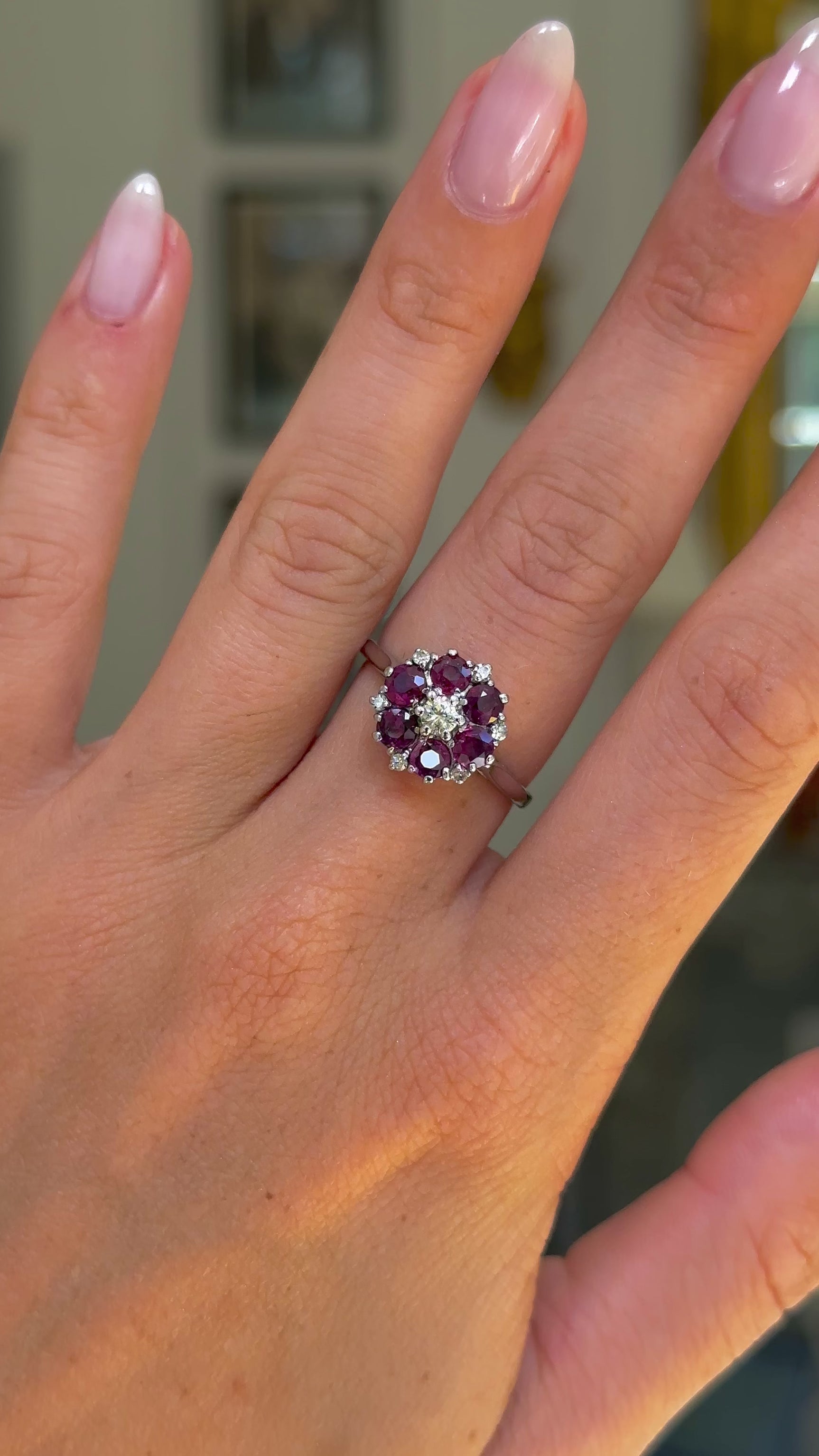 ruby and diamond cluster ring, worn on hand and moved away from lens to give perspective. 