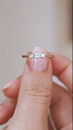 Video close-up of the Edwardian three-stone ring balanced on a fingertip, highlighting its platinum and yellow gold setting.