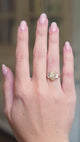 Vintage yellow oval diamond and half-moon diamond three-stone ring worn on hand shown in motion.